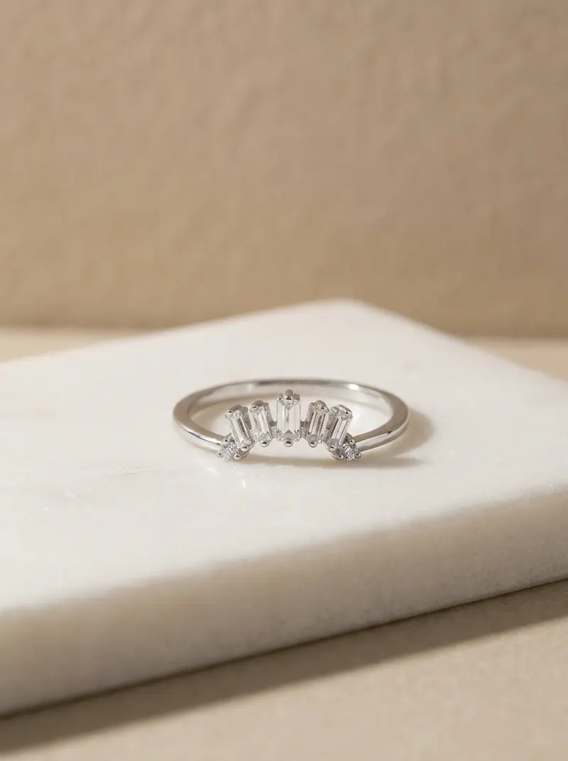 Silver baguette crown ring lying flat on an ivory slab