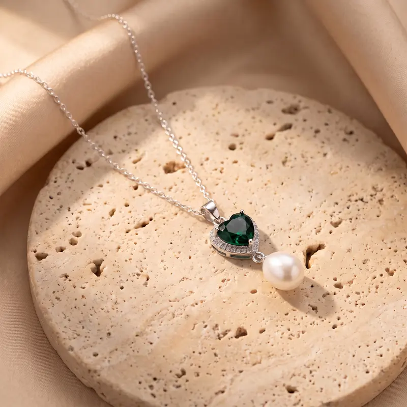 Emerald-green heart and pearl pendant on a travertine disc