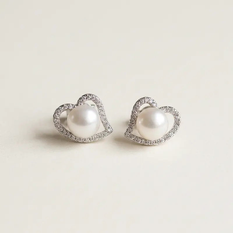 Pair of heart halo pearl studs on a warm off-white surface
