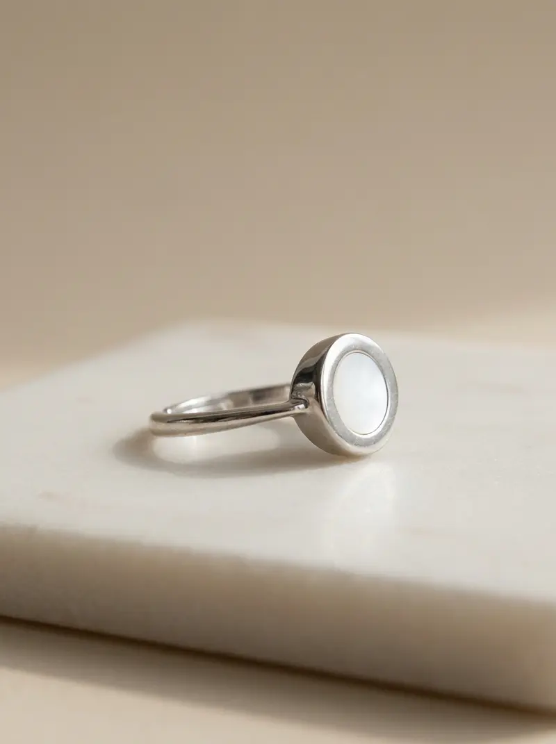 Mother-of-pearl round ring resting on an ivory slab