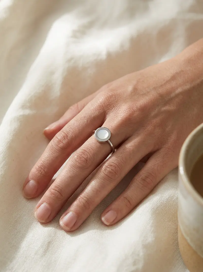 Hand on ivory linen wearing the mother-of-pearl ring
