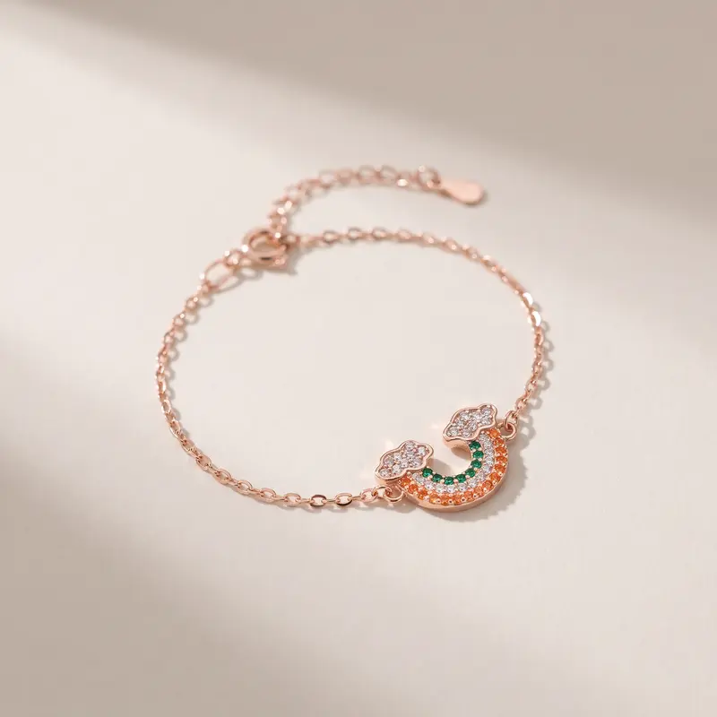 Rose-gold-finish rainbow cloud bracelet on an off-white surface