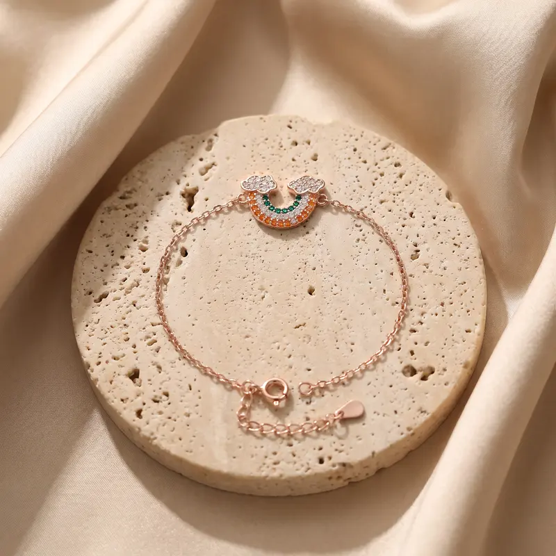 Rose-gold-finish rainbow cloud bracelet on a travertine disc