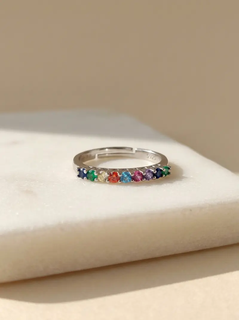 Silver rainbow stone ring lying flat on an ivory slab